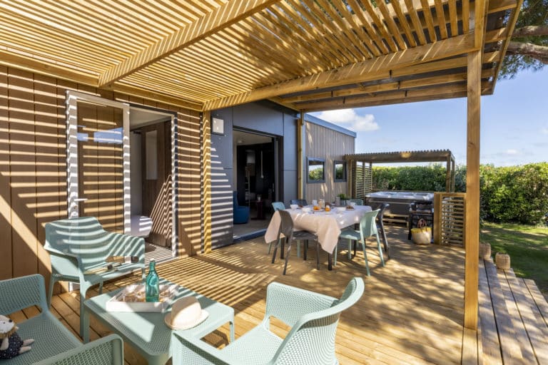 Terrasse en bois avec pergola et chaises extérieures.