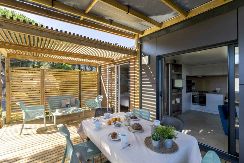 Sunny patio with a set table and a modern kitchen.